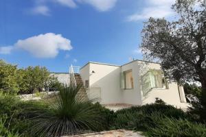 a white house with some plants in front of it at trullo fino in Cisternino