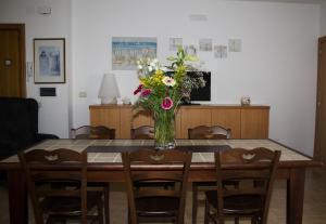 - une table à manger avec un vase de fleurs dans l'établissement B&B Virolì, à Vieste