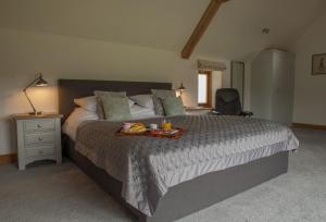 a bedroom with a large bed with a tray of fruit on it at Goose Run Cottage in Corscombe