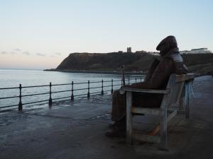 a statue of a person sitting on a bench near the water at Hotel Ellenby in Scarborough