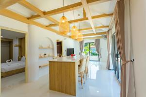 a kitchen and living room with a dining area and a bedroom at Neenlawat Riverside in Suratthani