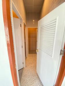 a hallway with a white door and a tiled floor at Baan Hall Hostel in Khon Kaen