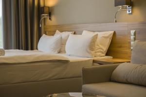 Pokój hotelowy z łóżkiem z białymi poduszkami i kanapą w obiekcie Baltic Plaza Hotel Medi Spa w Kołobrzegu