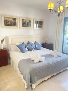 1 dormitorio con 1 cama grande con almohadas azules y blancas en Homey Home Guadalvillas 91 en Marbella