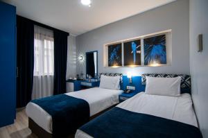 2 camas en una habitación de hotel con paredes azules en Lapis Inn Hotel & Spa ( Ex. Ambassador Hotel) en Estambul