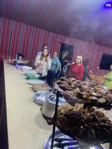 a group of people standing around a table with food at Experience sleep under the star in Wadi Rum