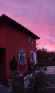 una casa roja con una puesta de sol en el fondo en Alloggio Turistico Dakota, en Manziana