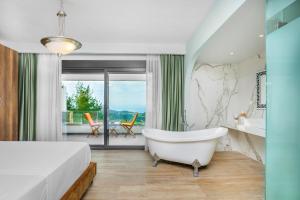 1 dormitorio con bañera, 1 cama y balcón en Epta Villas Luxury Redefined en Agia Paraskevi