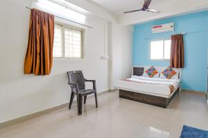 a bedroom with a bed and a chair in it at FabHotel Ashiyana Lodge in Pune