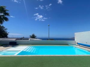 una gran piscina azul con el océano en el fondo en Malibú Ocean Villa, en Santa Cruz de Tenerife