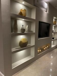 Habitación con estanterías con jarrones y TV. en أفخم شقة فندقيه بالقرب من الحرم المكي en Makkah