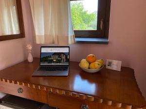 a laptop on a wooden table with a bowl of fruit at La Porta delle Gole in Motta Camastra