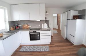 a white kitchen with white cabinets and a refrigerator at Wiesenschlössle in Sagard