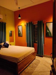 a bedroom with a bed with orange walls and blue curtains at Housefull Residency in Khandagiri