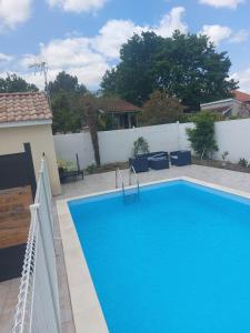 una gran piscina azul junto a una valla blanca en petite maison sympathique plein de charme, en Beychac-et-Caillau