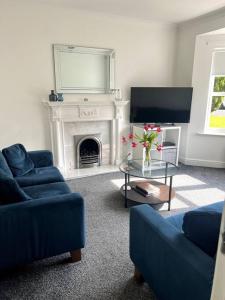 sala de estar con 2 sofás azules y chimenea en Home2Home Meadow House en East Kilbride