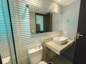 een badkamer met een wastafel, een toilet en een spiegel bij Pousada La Acolhida in Cabo Frio