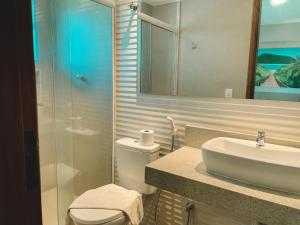 a bathroom with a sink and a toilet and a mirror at Pousada La Acolhida in Cabo Frio