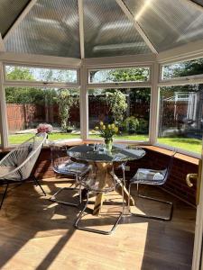 a screened in porch with a table and chairs at Home2Home Meadow House in East Kilbride