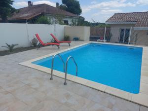 una piscina con 2 sillas junto a una casa en petite maison sympathique plein de charme, en Beychac-et-Caillau
