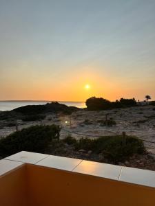 einen Sonnenuntergang am Strand mit Sonnenuntergang über dem Meer in der Unterkunft Arenas del Mar Formentera in Es Arenals