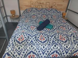 a bed with a blue and white quilt with a remote control on it at petite maison sympathique plein de charme in Beychac-et-Caillau