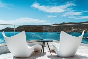 two white chairs and a table on a balcony at Apollo Resort in Agia Marina Aegina