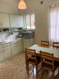 cocina con mesa, sillas y microondas en Lillian’s House, en Atenas