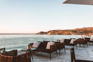 a restaurant with chairs and tables and a view of the water at Apollo Resort in Agia Marina Aegina