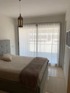 - une chambre avec un grand lit et une grande fenêtre dans l'établissement Appartement pied dans l’eau à 10 min d’Agadir, à Aourir