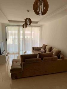 - un salon avec un canapé et une table dans l'établissement Appartement pied dans l’eau à 10 min d’Agadir, à Aourir