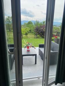 eine offene Glasschiebetür mit einem Tisch mit Blumen auf der Terrasse in der Unterkunft Mala Oaza in Čačak