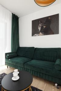 een groene bank in een woonkamer met een zwarte tafel bij Słoneczny apartament z Parkingiem w cenie !!! in Kołobrzeg