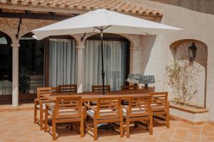 einen Holztisch und Stühle mit Sonnenschirm in der Unterkunft Villa Ventisca in Platja  d'Aro
