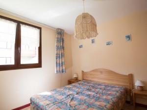 a bedroom with a bed and a window and a chandelier at Appartement Lanslebourg-Mont-Cenis, 3 pièces, 7 personnes - FR-1-508-98 in Lanslebourg-Mont-Cenis
