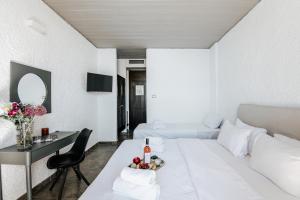 a white living room with a white bed and a table at Apollo Resort in Agia Marina Aegina