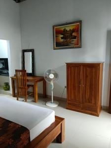 a bedroom with a bed and a desk and a fan at Lumbung Sari Home Stay in Amed