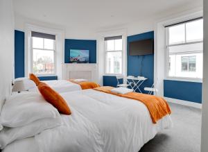 ベリック・アポン・トゥィードにあるHomesly Guest Rooms, Comfortable En-suite Guest Rooms with Free Parking and Self Check-inの青い壁と窓が特徴の客室で、ベッド2台が備わります。