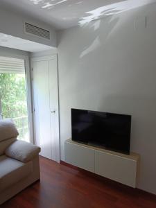 uma sala de estar com uma televisão de ecrã plano numa parede branca em Lyrioshomes Apartamento Filpo Rojas , Sevilla em Sevilha