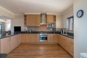 a kitchen with wooden cabinets and a clock on the wall at SW2 - Pezula Luxury Villa in Knysna