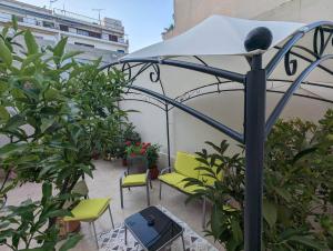 een patio met groene stoelen en een parasol bij cozy minimal apartment in Piraeus