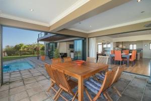 a dining room with a wooden table and chairs at Pezula Luxury Villa SW2 in Knysna