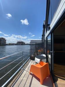 an orange bench on a balcony overlooking the water at Floating Apartments - ODRA DREAM in Szczecin