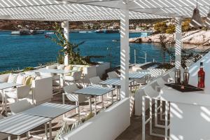 a row of tables and chairs on a balcony with the water at Apollo Resort in Agia Marina Aegina