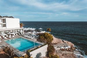 a hotel with a swimming pool next to the ocean at Apollo Resort in Agia Marina Aegina