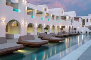 a swimming pool with chaise lounges in a resort at Apeiron Blue Santorini - Sustainable Adults Only 14 Plus in Fira