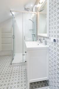 a white bathroom with a shower and a sink at Apartamenty Defala i Strefa Relaksu Natural Touch in Rymanów-Zdrój