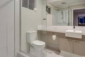 a white bathroom with a toilet and a sink at Apartment close to the beach in Jindalee