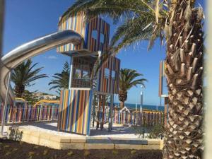 a playground with palm trees and a slide at Apartment close to the beach in Jindalee