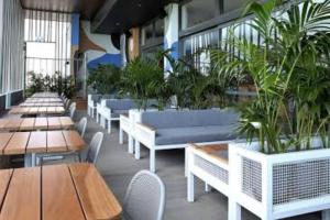 a restaurant with tables and chairs and potted plants at Apartment close to the beach in Jindalee